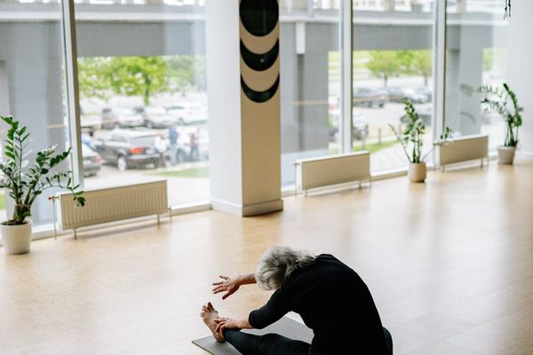 Woman in a calm, focused pose on a yoga mat in a minimalist room.